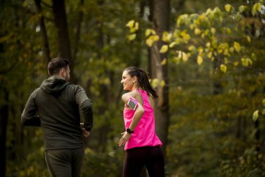 Atletik çift birlikte sonbaharda orman iz üzerinde çalışan