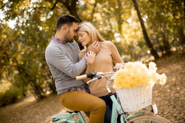 Bisiklet Altın Sonbahar Park ile birlikte sahip romantik aktif genç çift yürümek