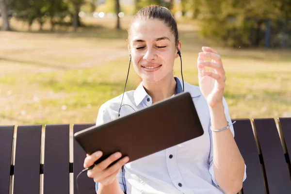Mujer Joven Sentada Banco Parque Escuchar Música Una Tableta — Foto de Stock