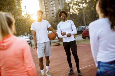 Gençlerin grup sahada basketbol oynarken çok ırklı