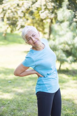 Parkta eğitim sırasında bir sırt ağrısı olan sportif kadın kıdemli