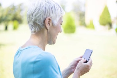 Akıllı telefon açık kullanarak giyim spor kadın kıdemli portresi
