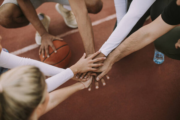 Вид сверху на баскетбольную команду, держащуюся за руки над кортом
