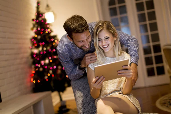 Handsome young couple with tablet at New Years eve at home