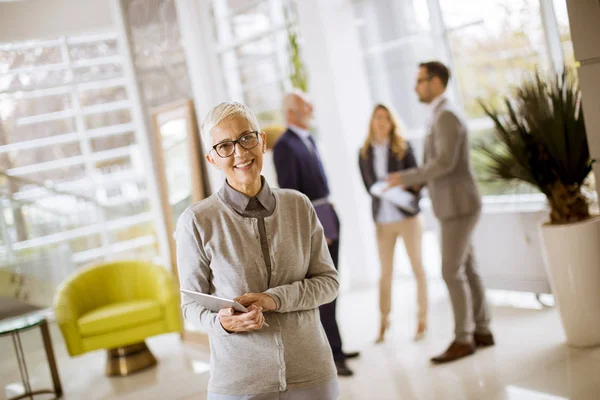 Portret Van Senior Zakenvrouw Permanent Met Digitale Tablet Terwijl Andere — Stockfoto