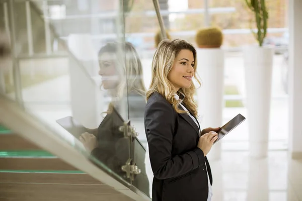 Cheerful young businesswoman with tablet in the modern office