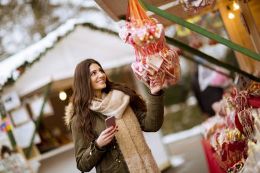 Telefonunuzun parkta soğuk kış gününde gülümseyen genç kadın portresi