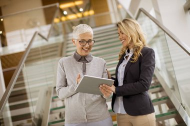 Office dijital tablet bakarak üst düzey ve genç iş kadınları portresi