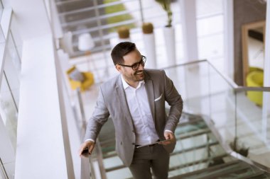 Modern ofis ayakta ve tablet kullanarak takım elbise giymiş mutlu işadamı