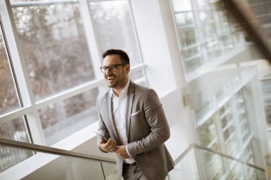 Modern ofis ayakta ve tablet kullanarak takım elbise giymiş mutlu işadamı