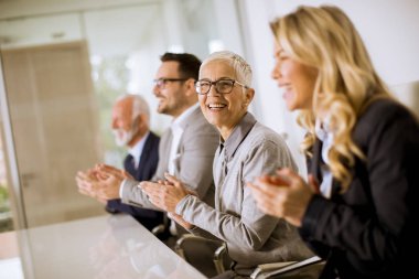 Satırda ofiste otururken memnun gurur iş takım Alkışlar eller