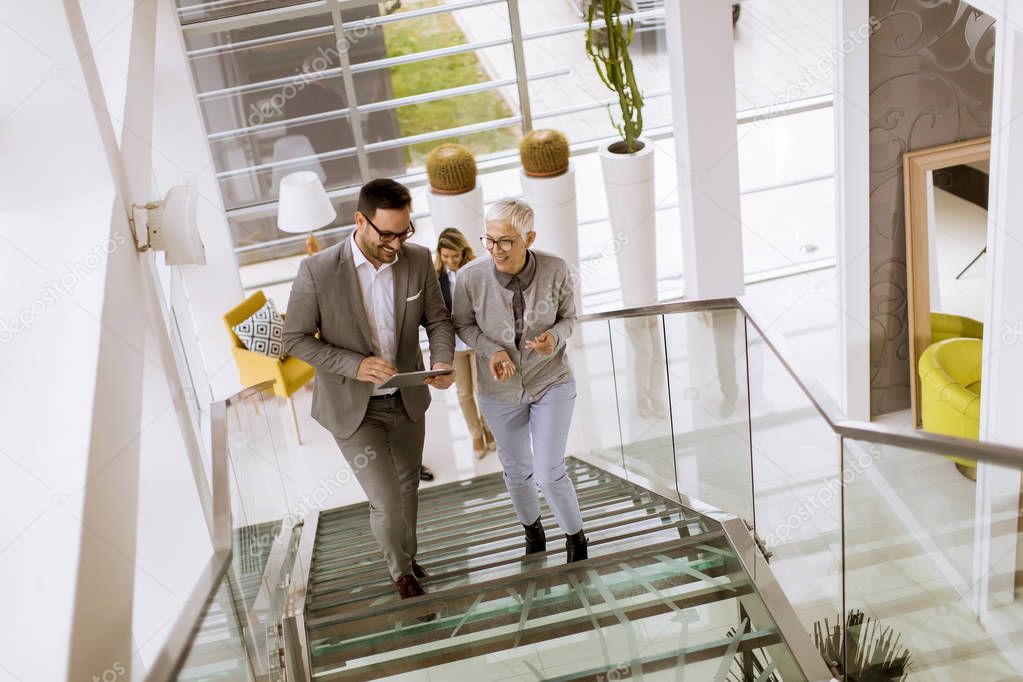 Group of businessmen and businesswomen walking and taking stairs in an office building