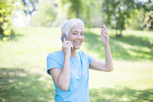 Closeup portrait of sporty senior lady on phone call in a park