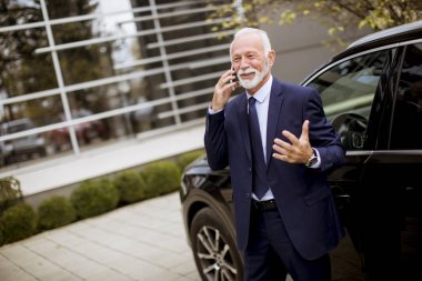 Cep telefonuyla car yakınındaki üst düzey işadamı portresi