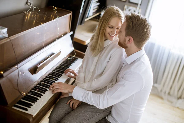 Loving young couple playing piano in the room at home