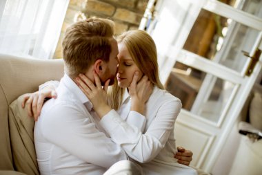 Kanepede oturan ve kanepeye sarılma sevgi dolu genç Çift