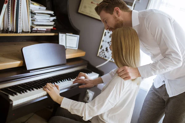 Loving young couple playing piano in the room at home