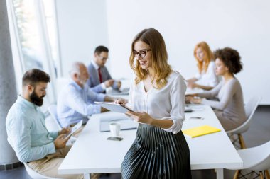 Genç çekici kadın Yöneticisi duran modern Office dijital tablet üzerinde çalışan