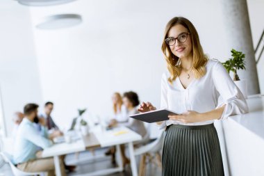 Genç çekici kadın Yöneticisi duran modern Office dijital tablet üzerinde çalışan
