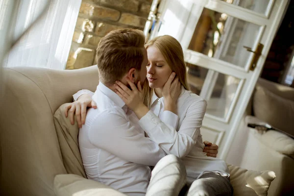 Kanepede oturan ve kanepeye sarılma sevgi dolu genç Çift