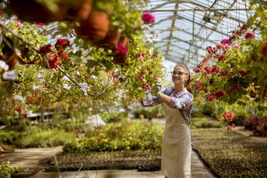 Sera içinde bahar çiçekleri ile çalışan genç ve güzel kadın