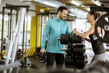 Onun kişisel antrenör yardımıyla bir spor salonunda genç kadın egzersiz