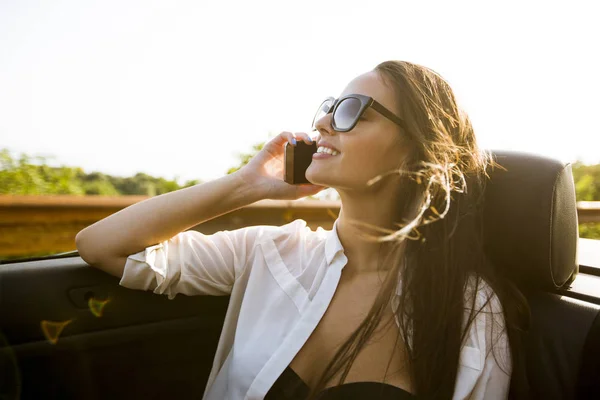 年轻女子使用移动电话 坐在敞篷跑车在夏季的一天 — 图库照片