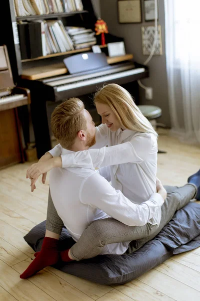 快乐和有爱心的年轻夫妇坐在房间的地板上接吻 — 图库照片
