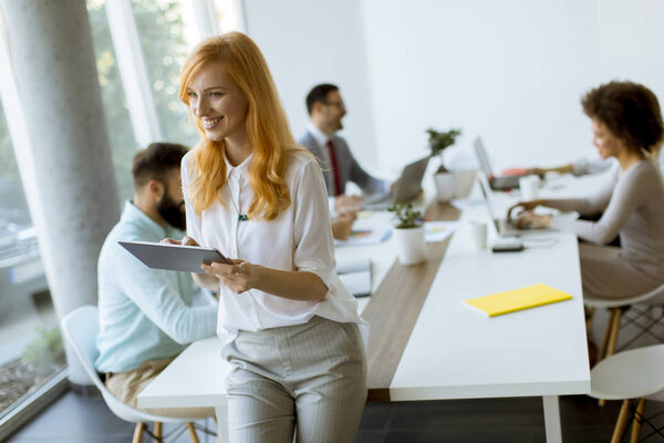 Pretty young red hair woman using digital tablet in the modern office