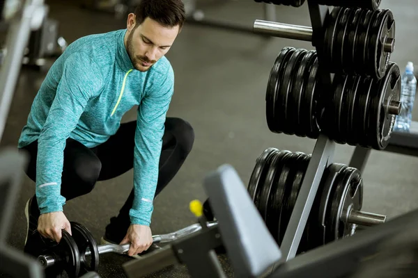 Yakışıklı genç adam eğitim salonunda dumbbells hazırlama