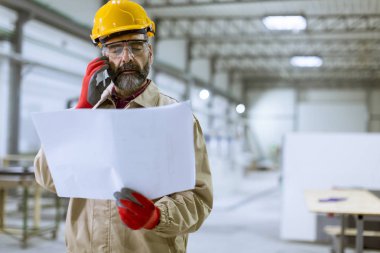 Plan seyir ve cep telefonuyla fabrikada yakışıklı olgun mühendisi