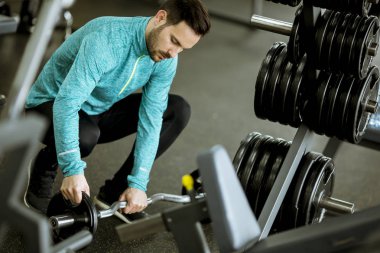 Yakışıklı genç adam eğitim salonunda dumbbells hazırlama