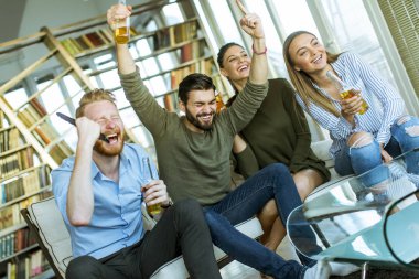 Group TV'ye bakıyor, elma şarabı içme ve having fun odaya genç arkadaşlar