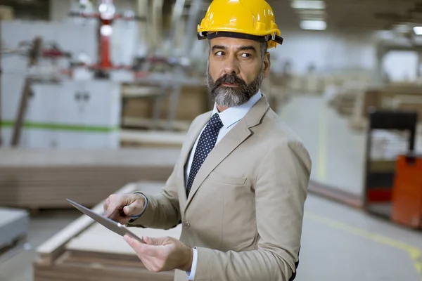 Portrait of middle-aged businessman with digital tablet in factory