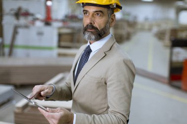 Fabrikada dijital tablet ile orta yaşlı işadamı portresi
