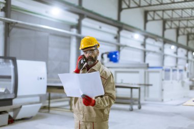 Plan seyir ve cep telefonuyla fabrikada yakışıklı olgun mühendisi