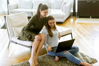 Genç kadın kanepe online alışveriş Web sitesi tarama yaparken rahatlatıcı üzerinde oturan gülümseyen