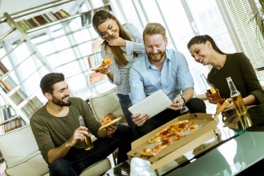 Pizza yemek, elma şarabı içme ve dijital tablet odasında izlerken gençlerin Grup