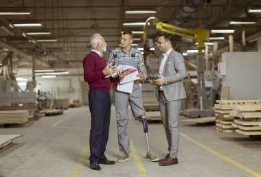 Üç adam portresi ayakta ve mobilya fabrikasında tartışmak