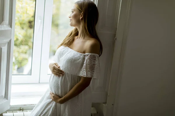 Ganska Ung Gravid Kvinna Som Står Vid Fönstret — Stockfoto