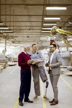 Üç adam portresi ayakta ve mobilya fabrikasında tartışmak
