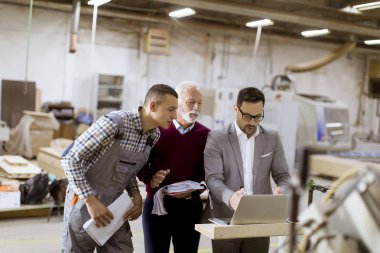 Üç adam portresi ayakta ve mobilya fabrikasında tartışmak