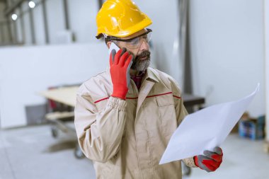 Plan seyir ve cep telefonuyla fabrikada yakışıklı olgun mühendisi