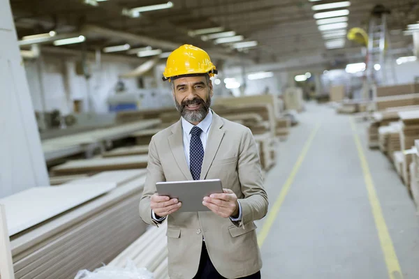 Portrait of middle-aged businessman with digital tablet in factory