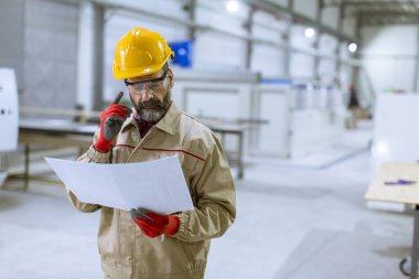 Fabrikada bir plan bakarak yakışıklı olgun mühendisi