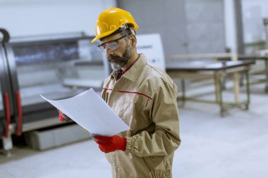 Fabrikada bir plan bakarak yakışıklı olgun mühendisi