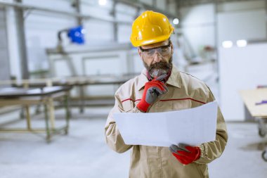 Fabrikada bir plan bakarak yakışıklı olgun mühendisi