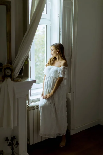 美丽的年轻孕妇站在窗口 — 图库照片
