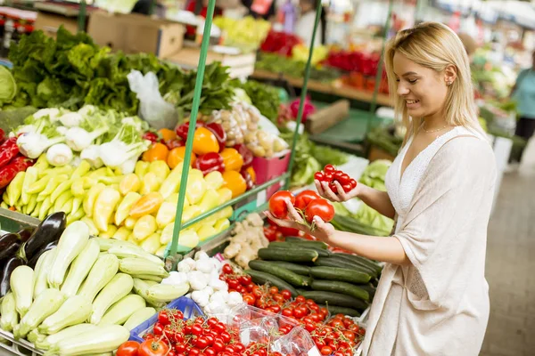 市場で野菜を買うのはかなり若い女性で表示します — ストック写真