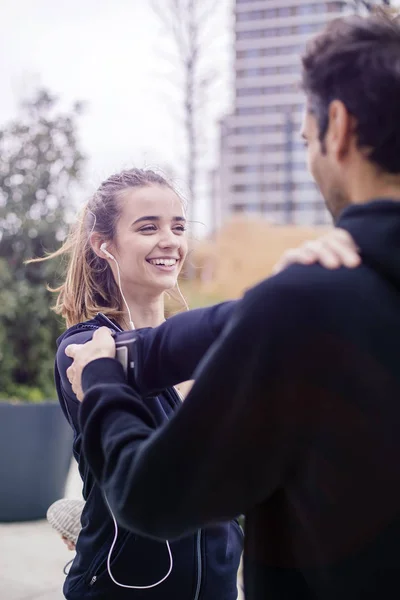 Male coach helping young woman exercising at outdoors in urban environment